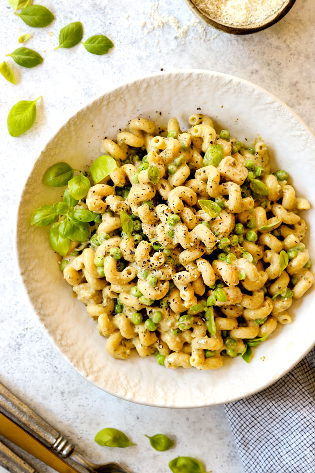 top view of chicken pesto pasta recipe in a white bowl garnished with basil