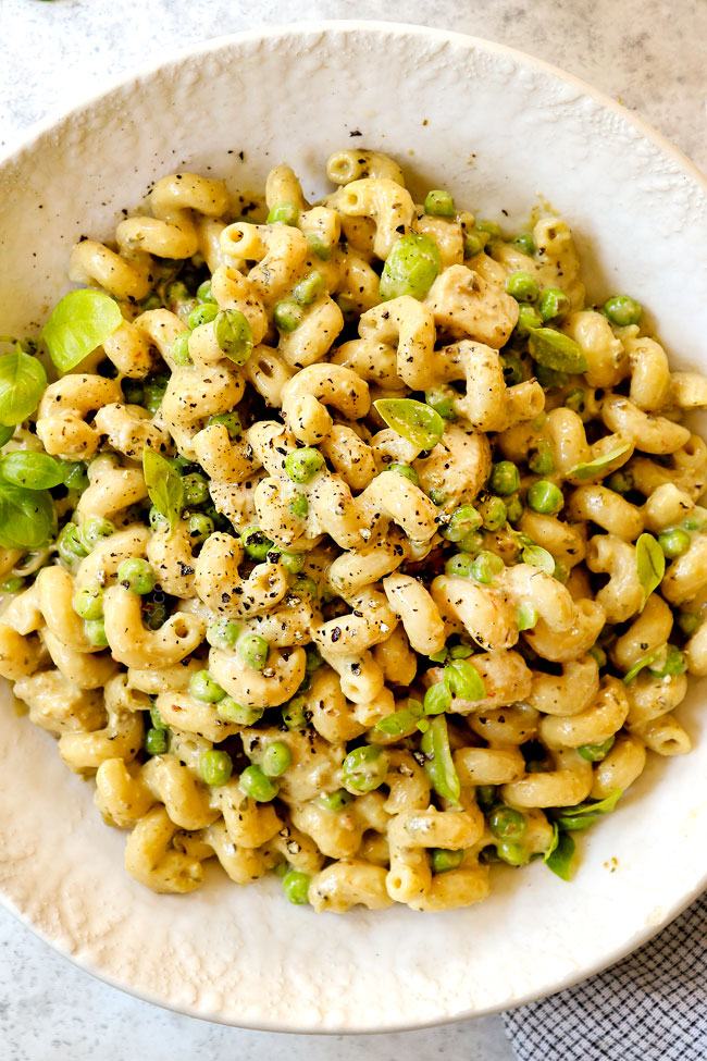 top view of creamy chicken pesto pasta with Parmesan and peas in a white bowl