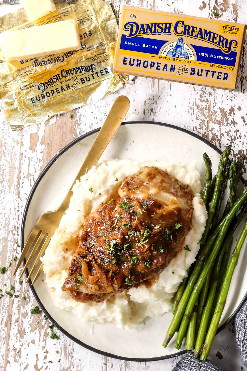 top view of a piece of French onion chicken on a plate with mashed potatoes with asparagus