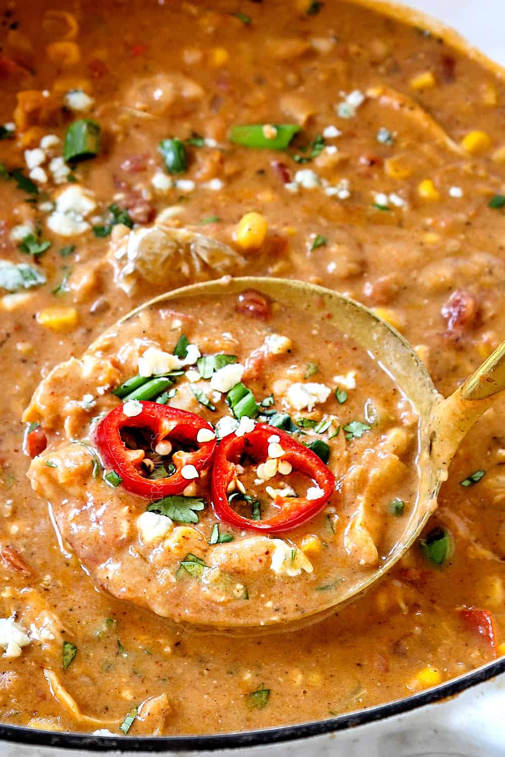 showing how to make buffalo chicken chili by stirring the chicken into the pot