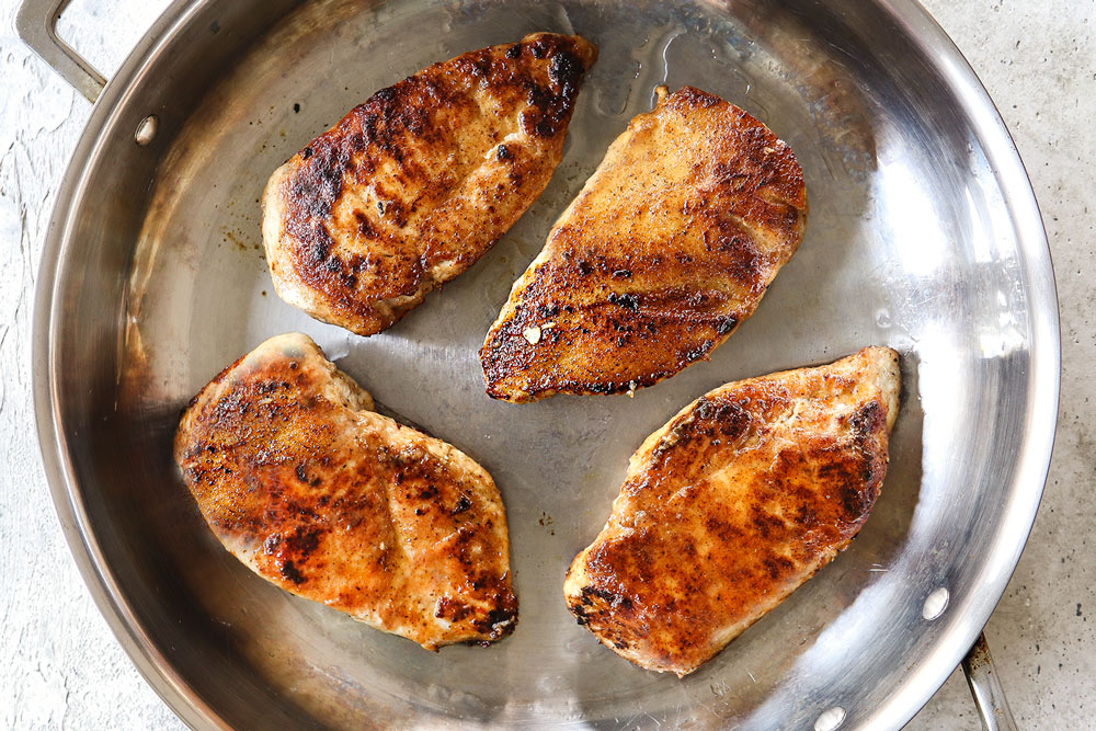 showing how to make creamy Chicken mushroom recipe by browning chicken in a stainless steel skillet