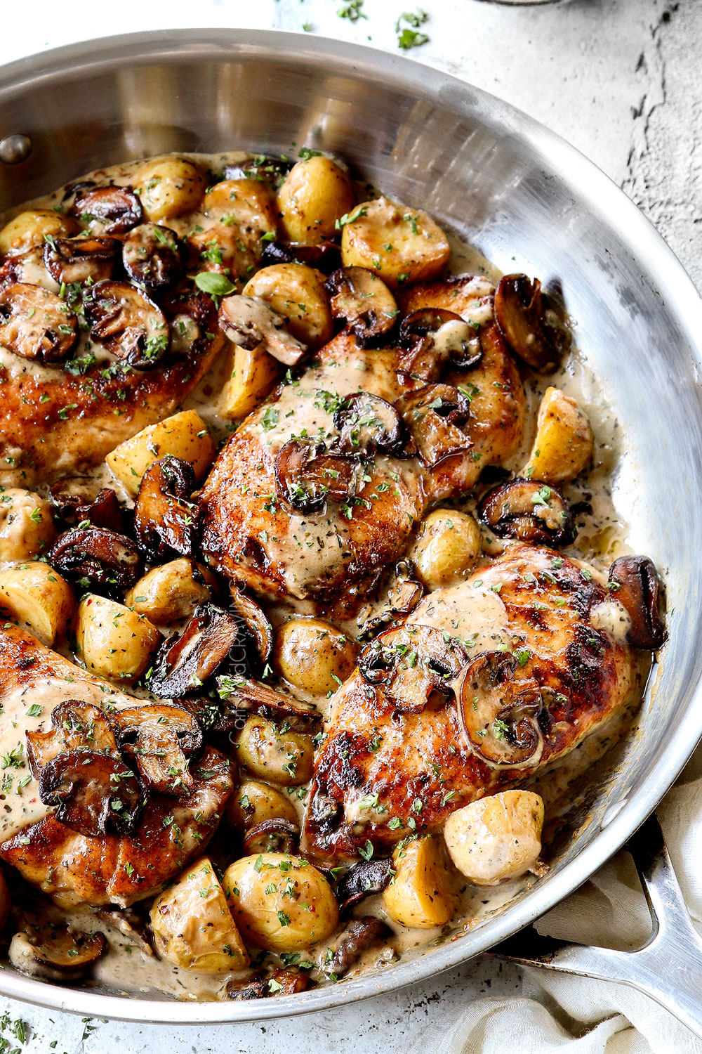showing how to serve creamy chicken mushroom recipe by garnishing chicken in a skillet