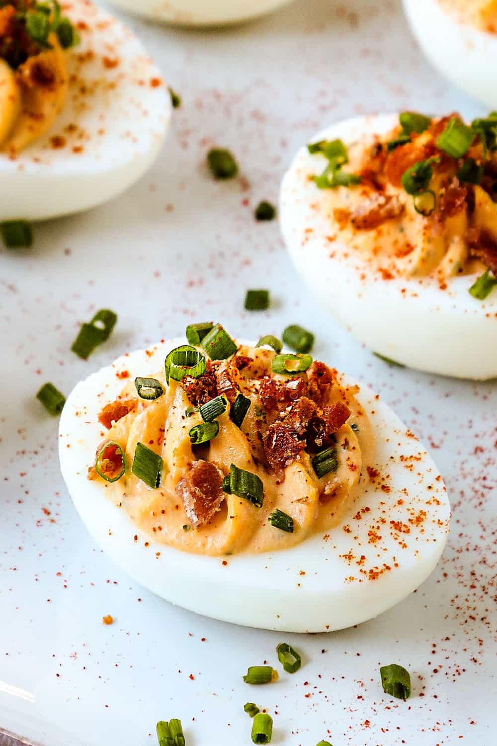 up close of best deviled eggs garnished with bacon and chives
