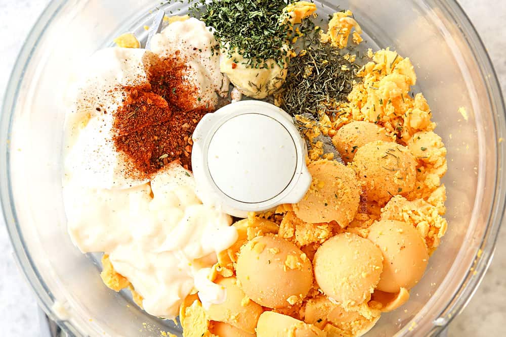 showing how to make best deviled eggs by adding egg yolks, mayonnaise, lemon juice and seasonings to a food processor