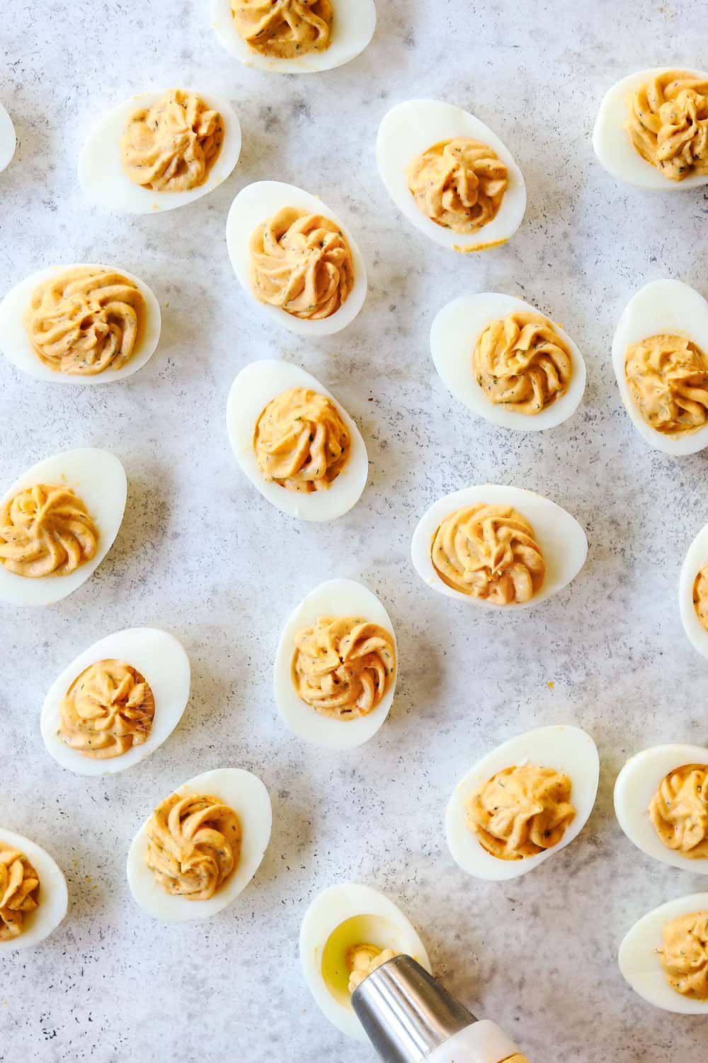 top view showing how to make deviled eggs by piping the filling into the eggs with a piping bag