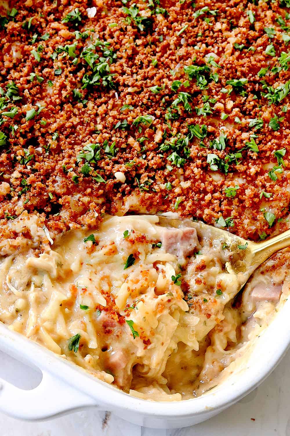 up close of a spoonful ham casserole in a 9x13 baking dish with panko
