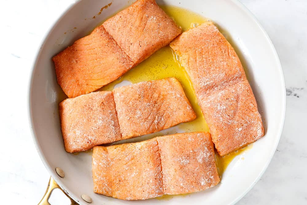 showing how to make honey glazed salmon recipe by searing the salmon in a skillet with vegetable oil