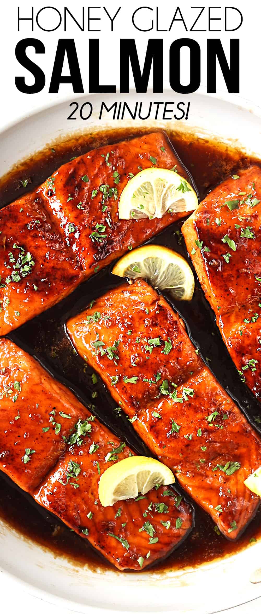 top view of honey garlic salmon in a white skillet garnished by lemon wedges