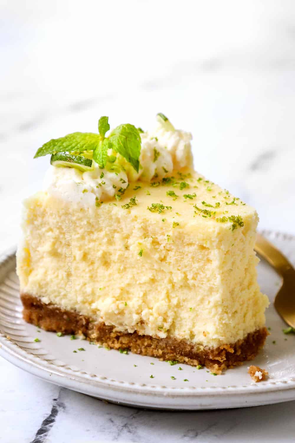 a slice of key lime cheesecake with a bite taken out of it showing how creamy it is