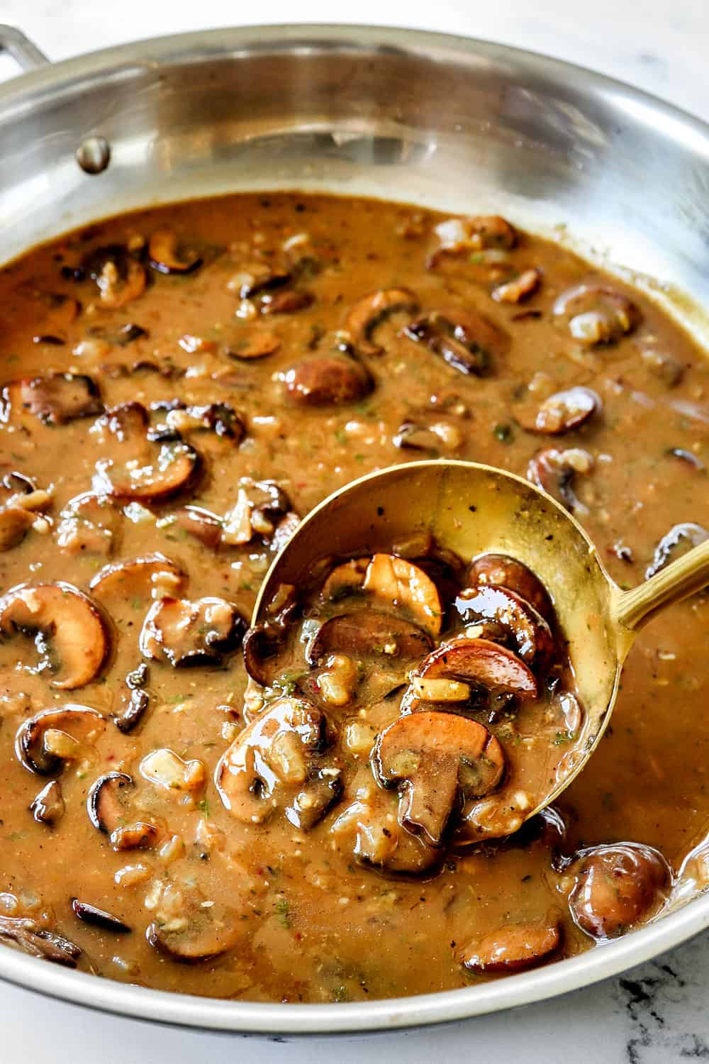 showing how to cook pork medallions recipe by simmering gravy until thickened