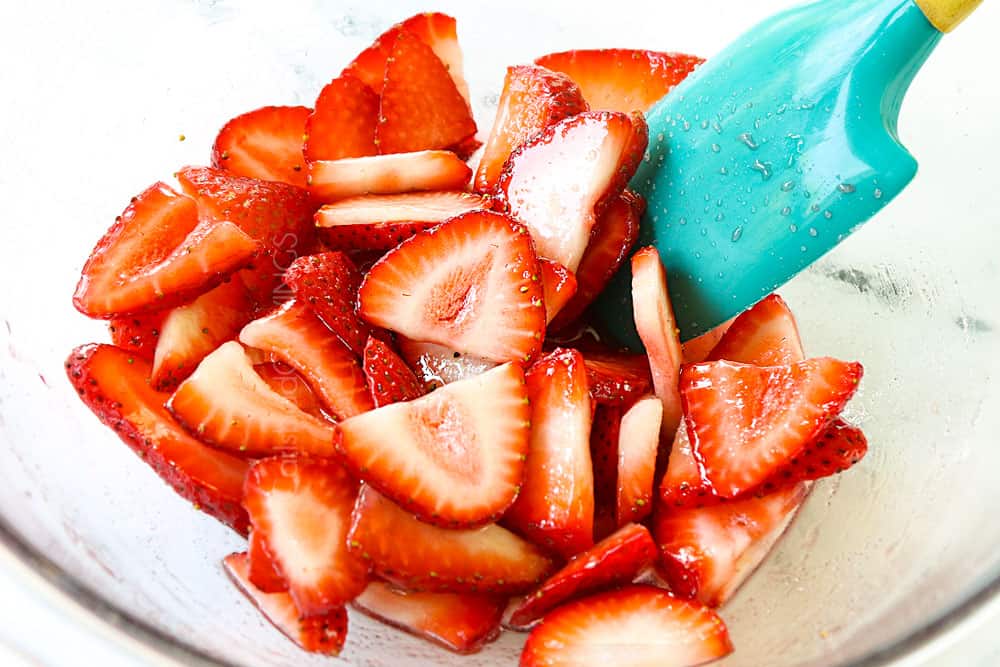 showing how to make stuffed French toast recipe by macerating sliced strawberries with sugar in a glass bowl