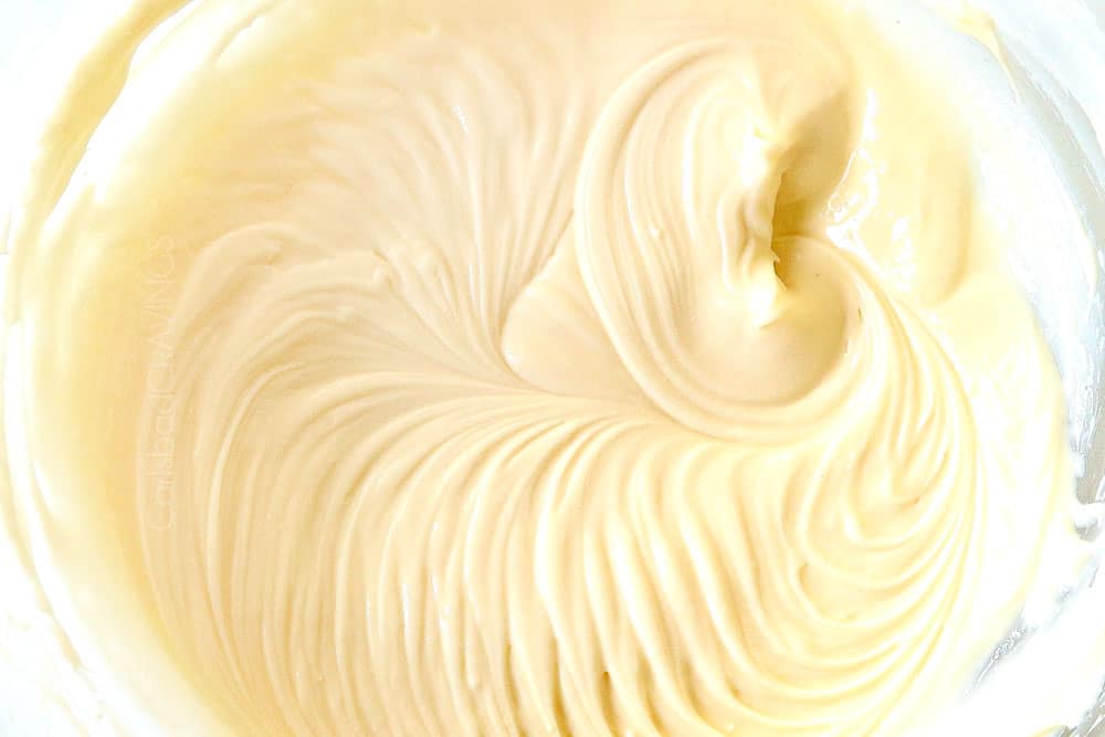 showing how to make stuffed French toast recipe by mixing cream cheese, sour cream and vanilla extract together in a glass bowl