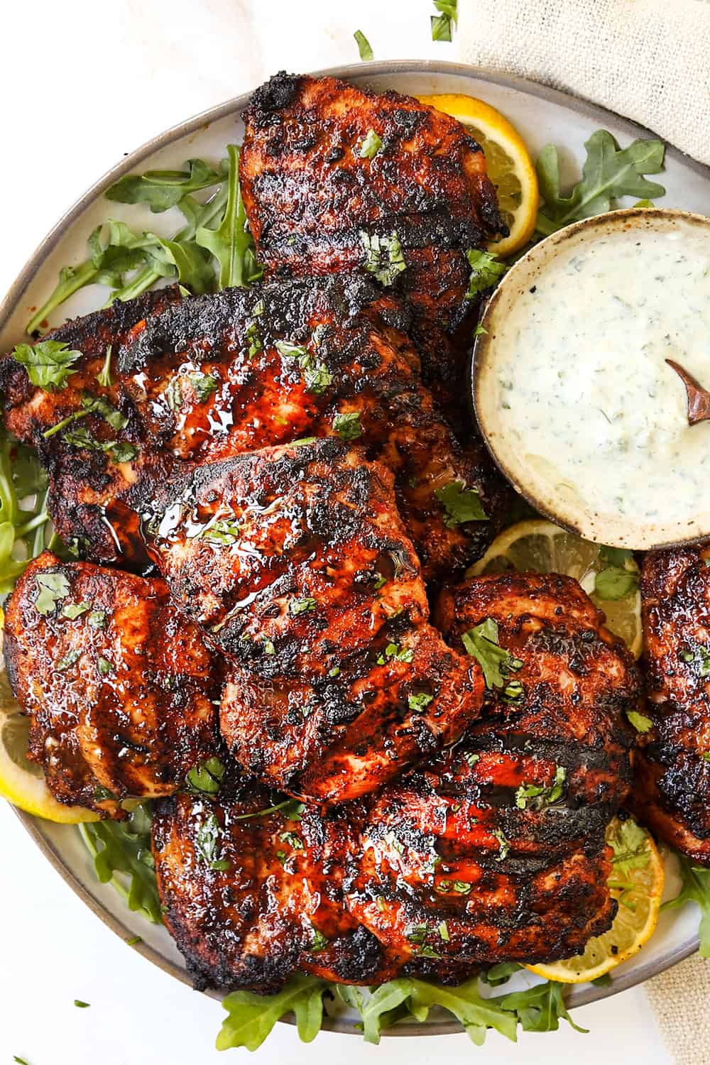 top view of harissa chicken recipe stacked on a white platter after grilling