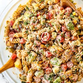 showing how to make Mexican Pasta salad by tossing the dressing and the ingredients together in a glass bowl