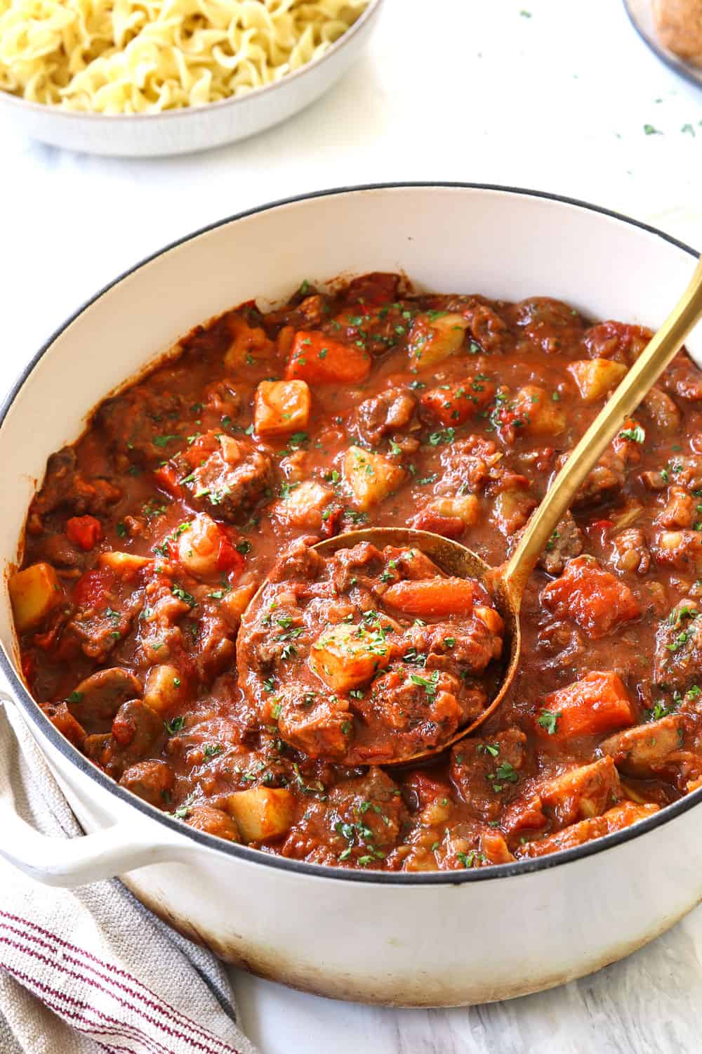 a ladle full of Goulash with beef, onions and potatoes