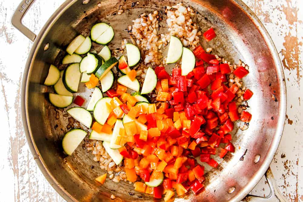 showing how to make shrimp pasta by sautéing bell peppers and zucchini in a stainless steel skillet