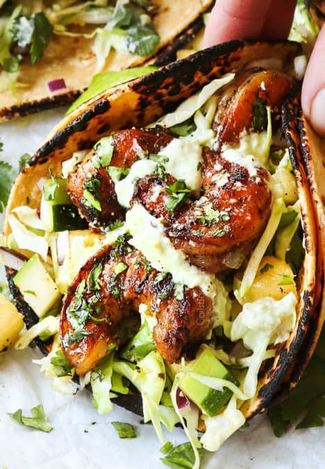 up close of showing how to make shrimp taco recipe by drizzling with avocado crema