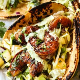 up close of showing how to make shrimp taco recipe by drizzling with avocado crema