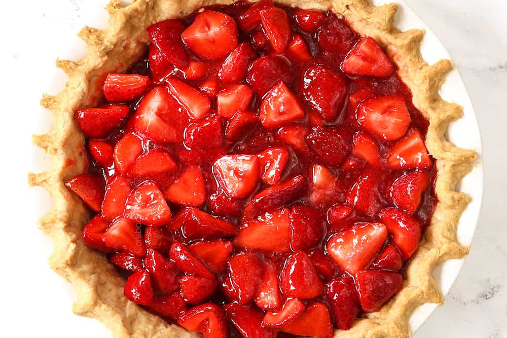 showing how to make fresh strawberry pie recipe by adding strawberry pie filling to the pie shell to chill