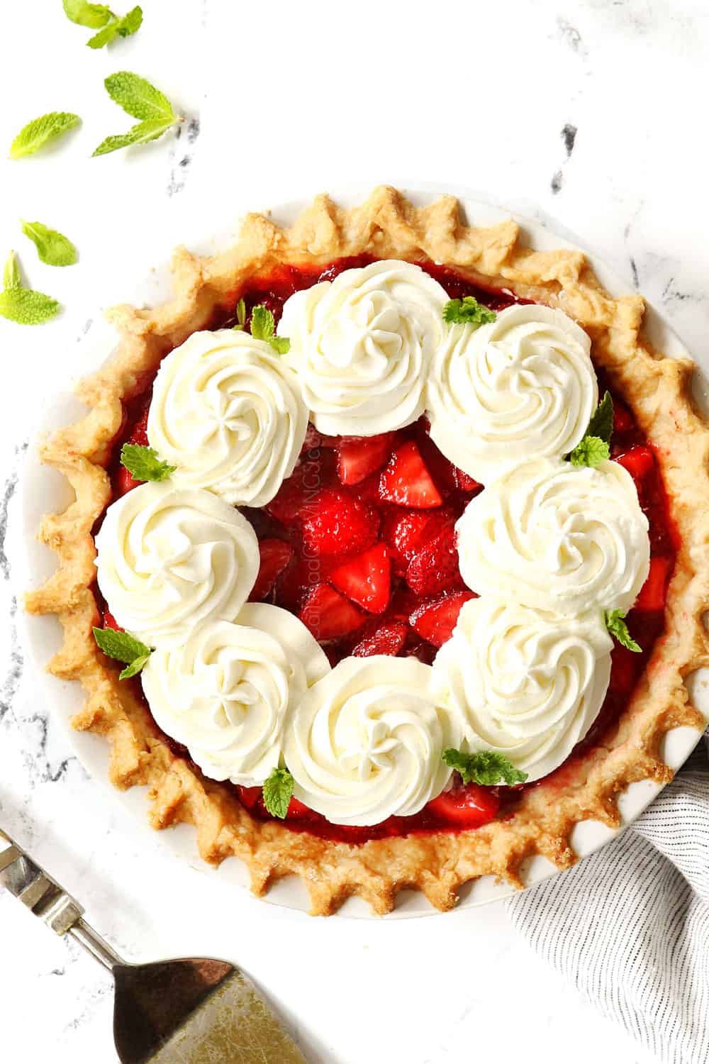 top view of fresh strawberry pie garnished with dollops of whipped cream