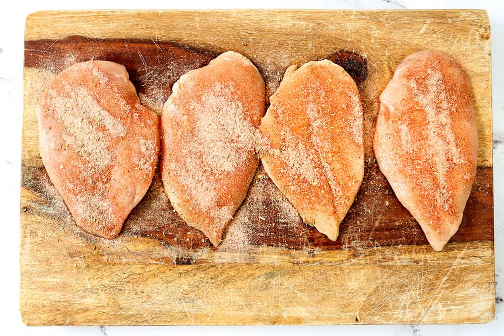 showing how to make blackened chicken Alfredo by seasoning chicken breasts with Cajun blackening seasoning