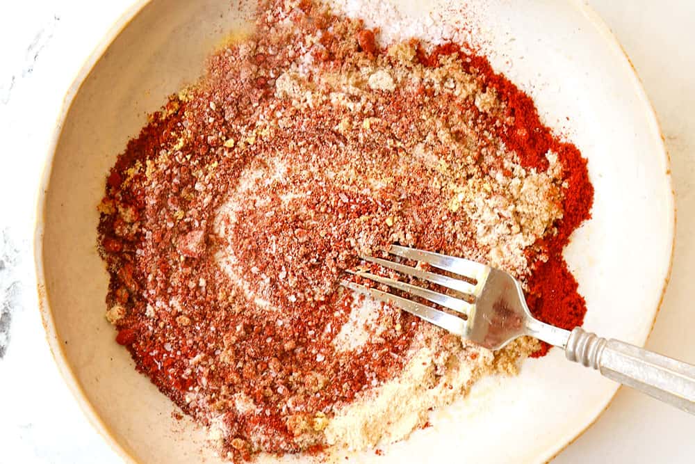 showing how to make grilled pork chop seasoning by whisking smoked paprika, chili powder, kosher salt, onion powder and garlic powder together in a bowl
