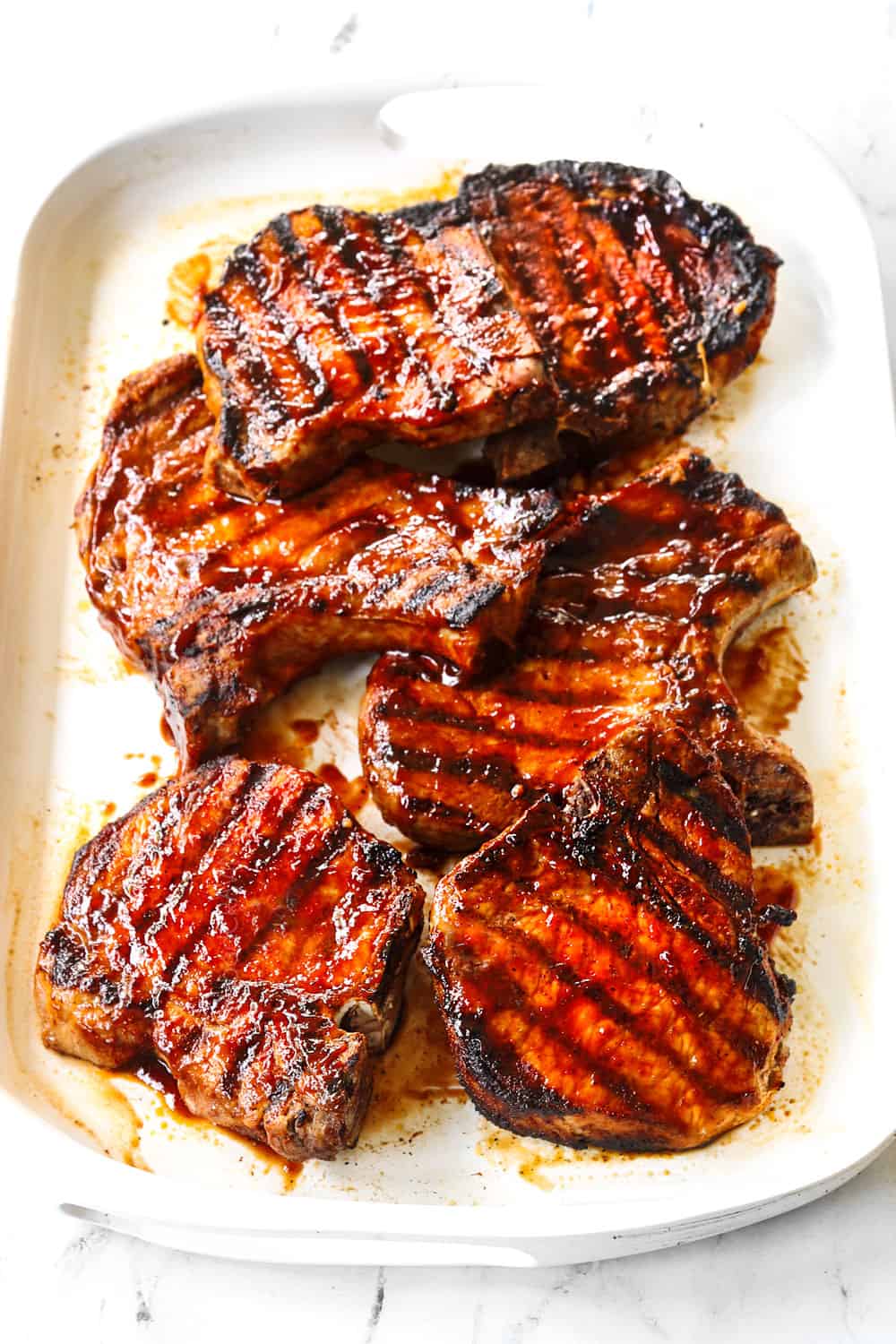 grilled bone in pork chops on a white platter