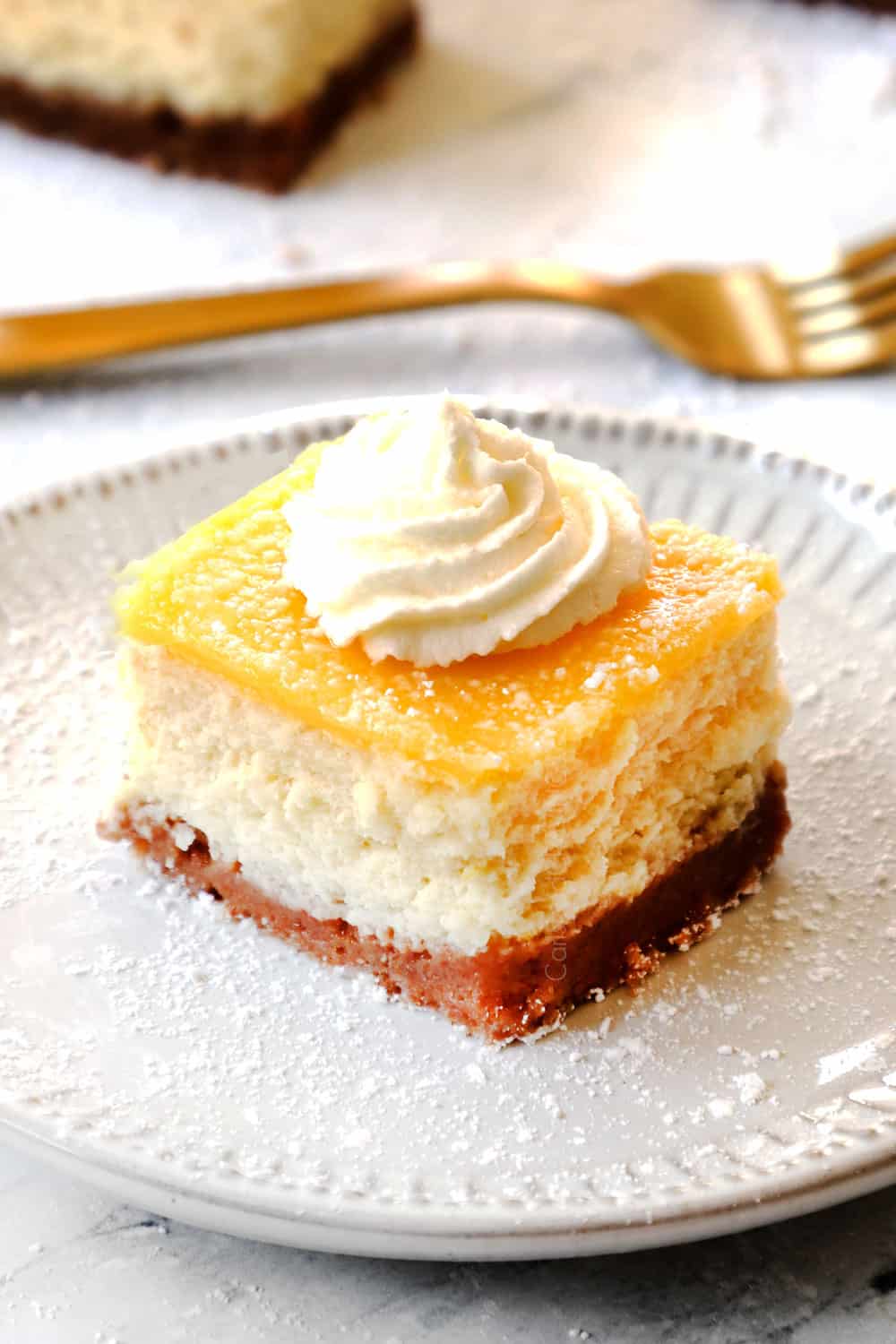 lemon cheesecake bar on a white plate dusted powdered sugar