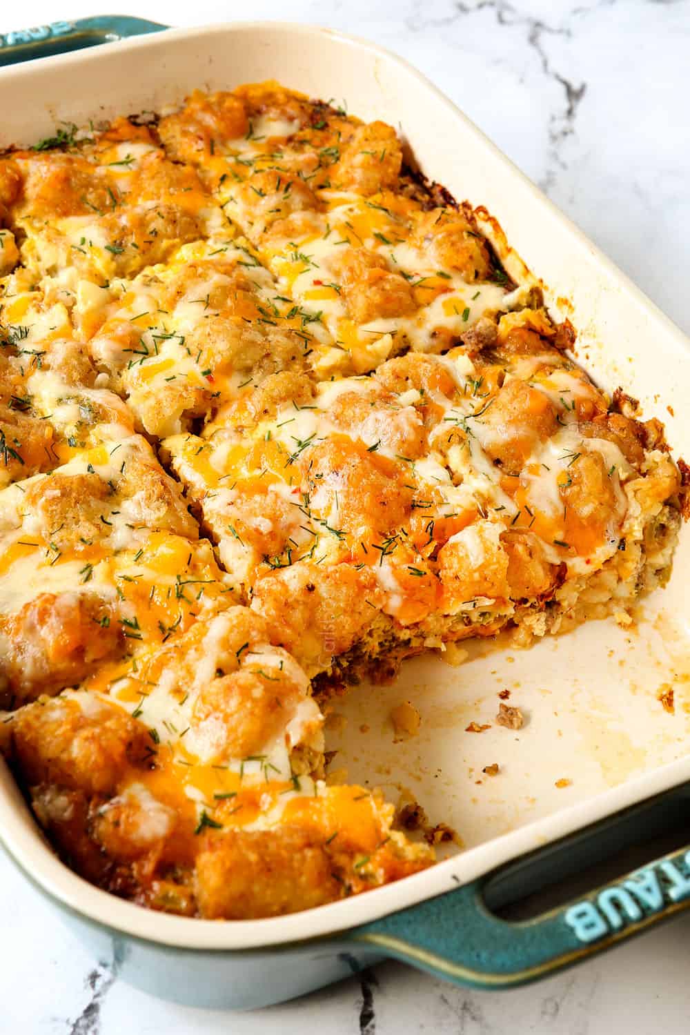 tater tot casserole in slices in a 9x13 baking dish with a few pieces missing showing how creamy it is