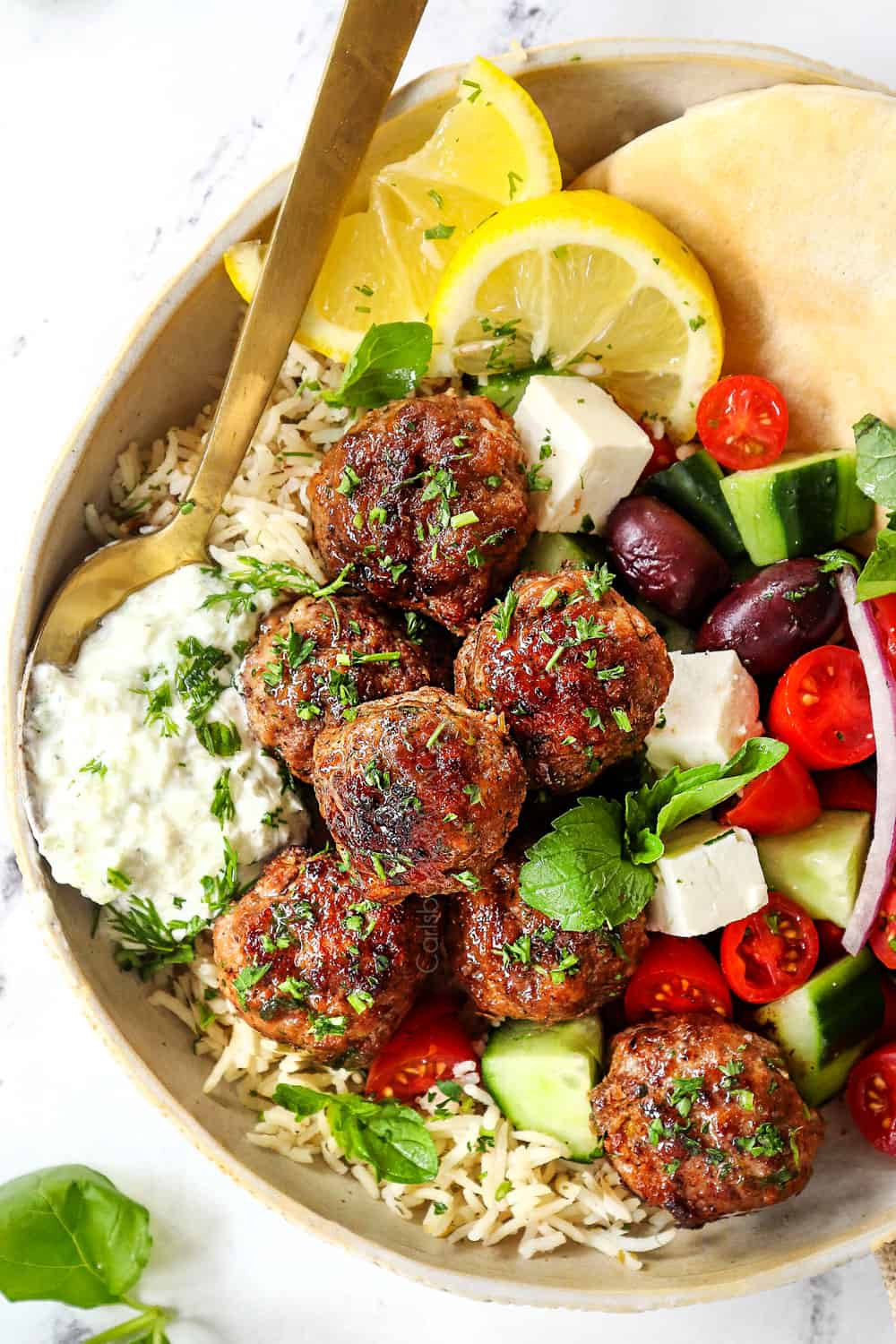 top view of Greek Meatball recipe (Keftedes) with lamb meatballs on a plate with tzatziki, rice, Greek salad and pita