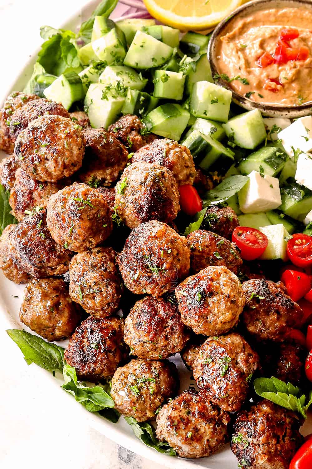 Greek Meatball recipe (Keftedes) with lamb meatballs on a platter with cucumbers and hummus