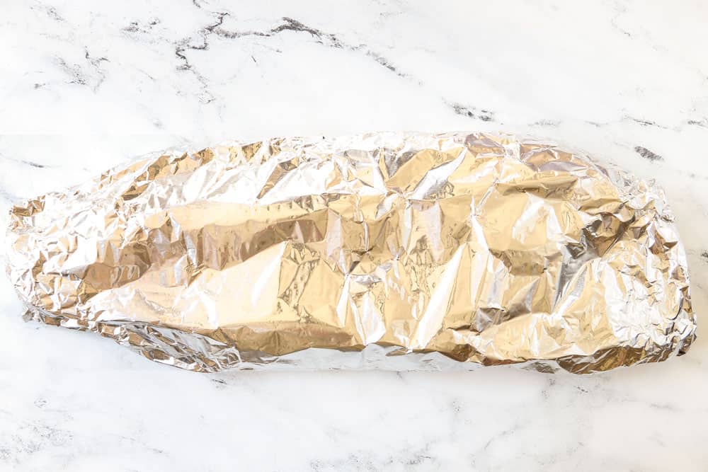 showing how to make grilled salmon in foil by sealing the salmon in foil