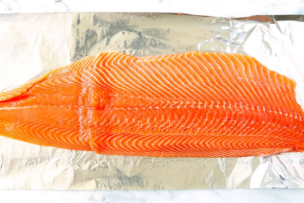 showing how to grill salmon in foil by adding salmon to heavy duty foil