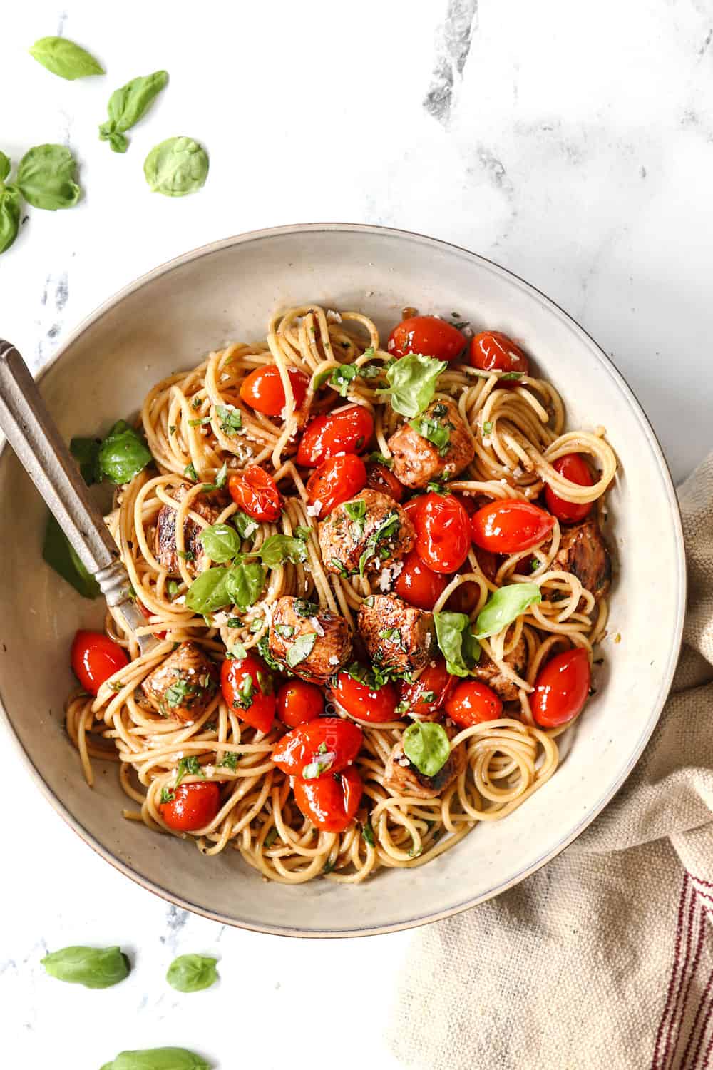 top view of bruschetta chicken pasta in a bowl with Parmesan and fresh basil