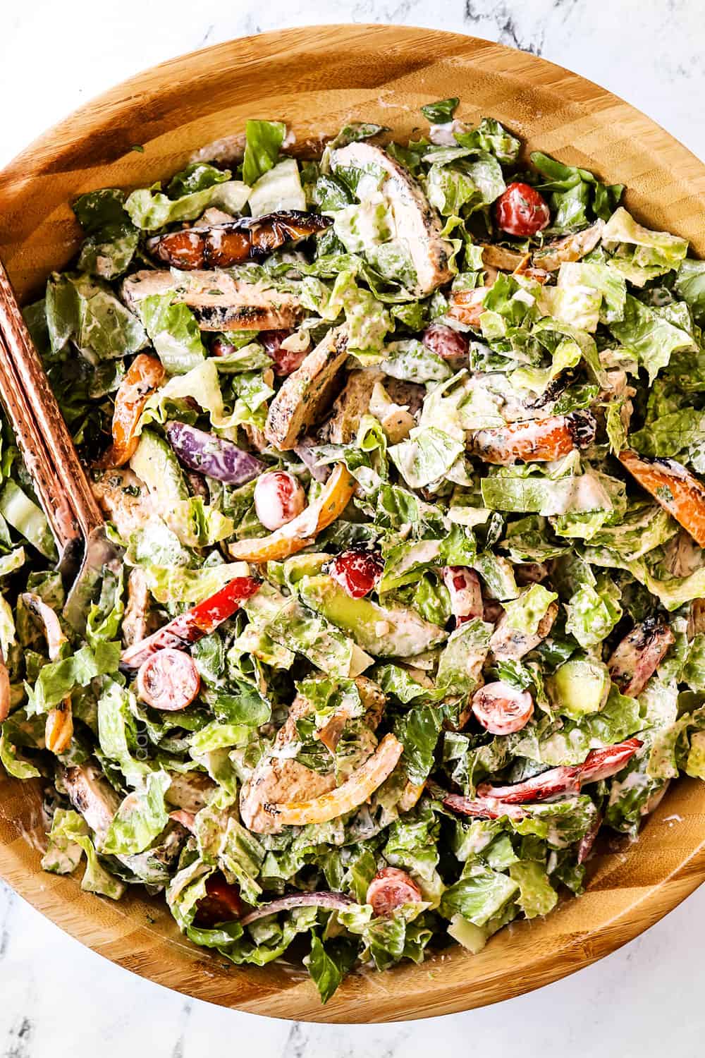 showing how to make chicken fajita salad by tossing with creamy dressing