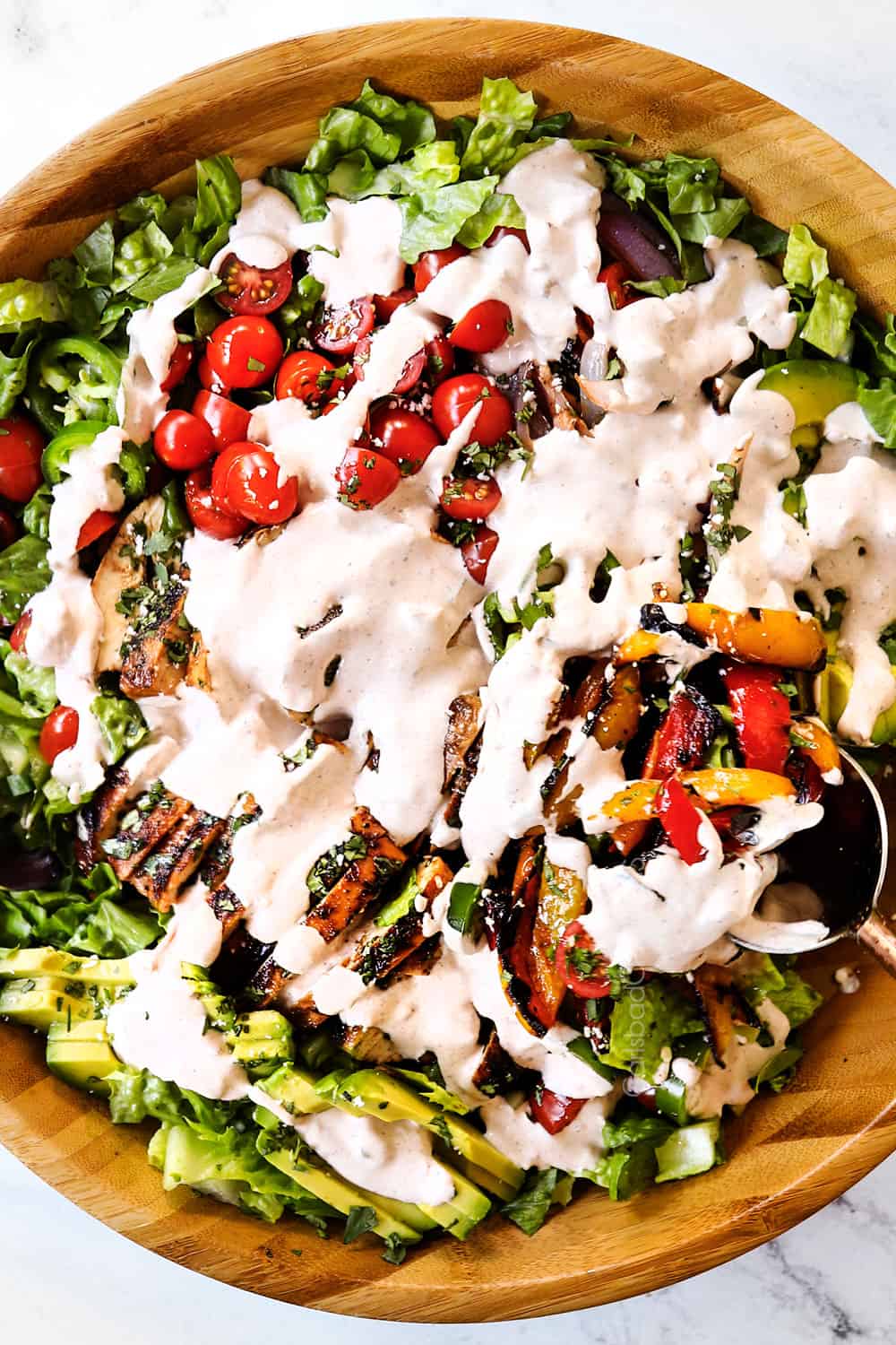 showing how to make chicken fajita salad by drizzling with creamy dressing