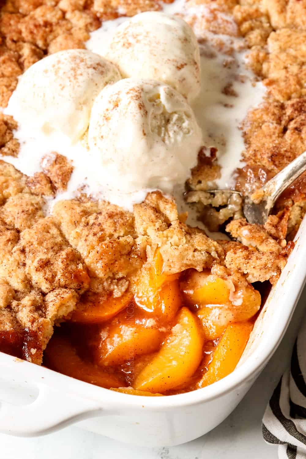 up close of scooping easy peach cobbler with fresh peaches