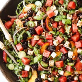 top view of a large serving bowl of watermelon salad with feta, basil, mint, cucumbers and arugula