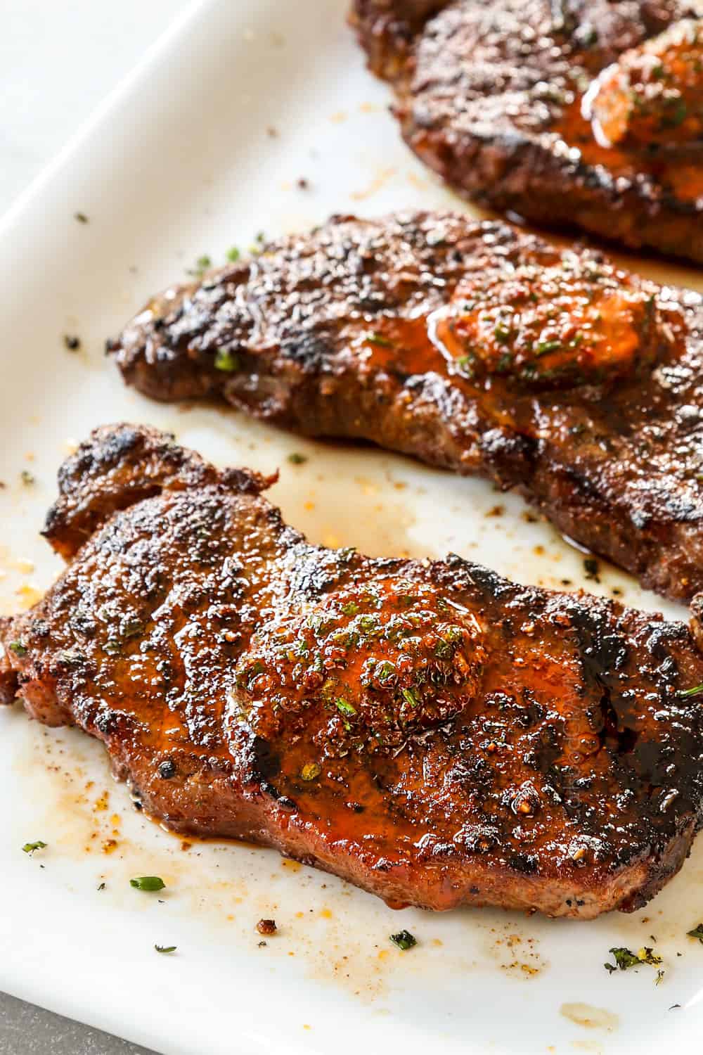 showing how to make New York Strip Steak (Strip Steak, NY Strip Steak) by adding compound butter to the top of the steaks