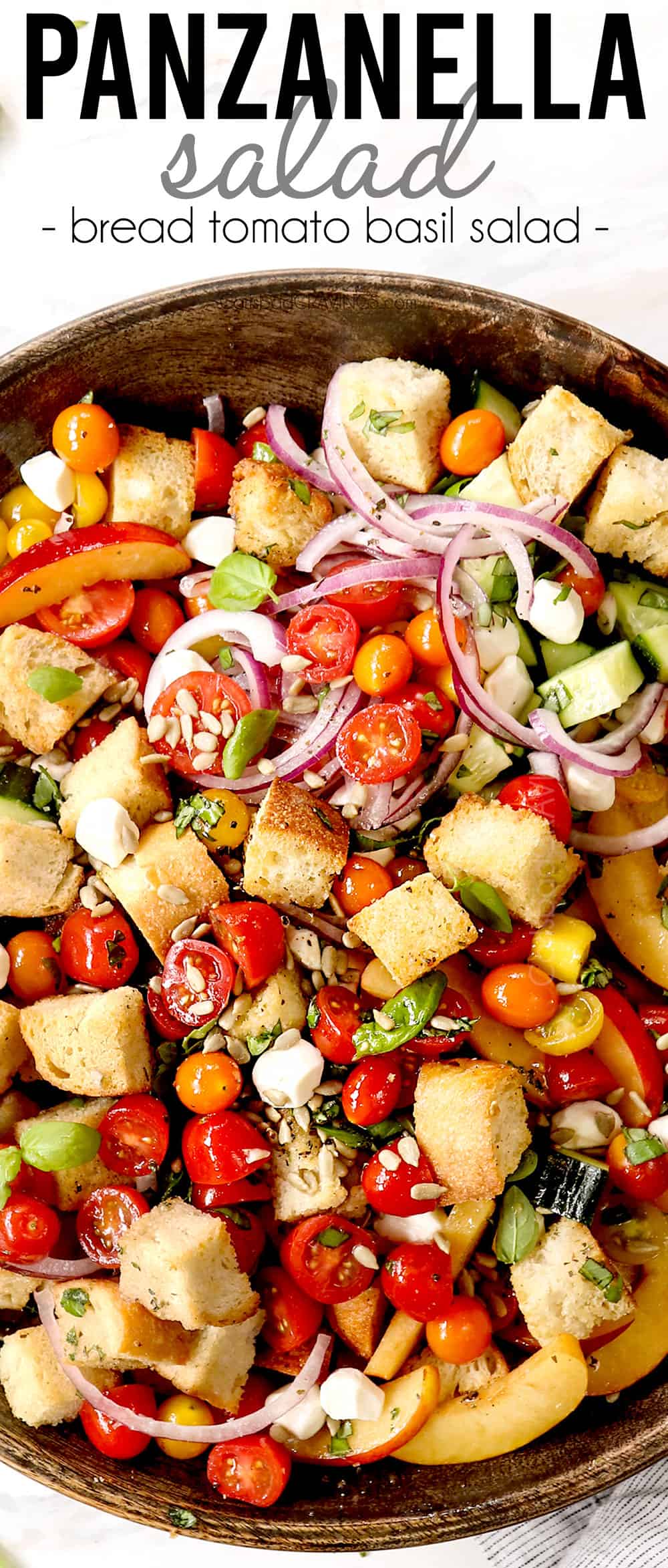 top view of panzanella in a wood serving bowl with tomatoes, red onions, cucumbers, basil, tomatoes and mozzarella