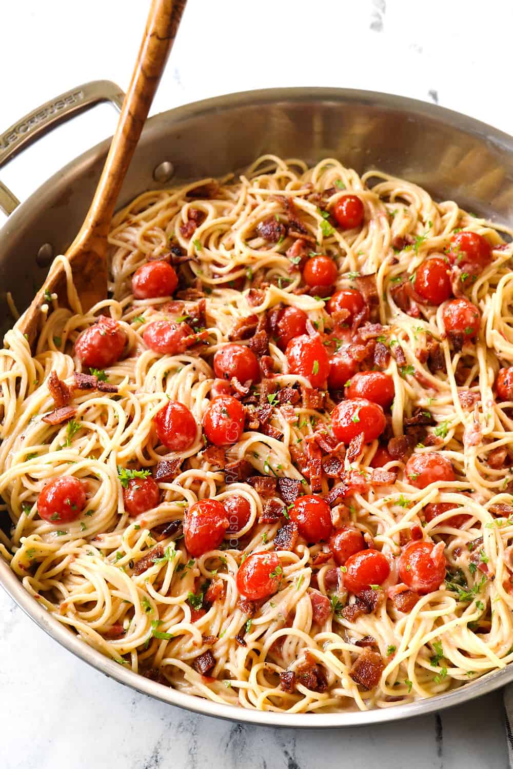 tomato bacon pasta in a skillet garnished by Parmesan
