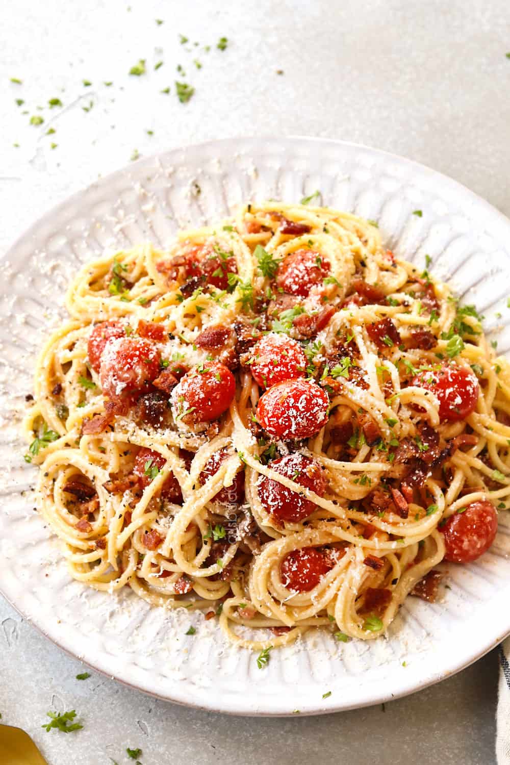 bacon pasta with tomatoes, garlic and Parmesan on a white plate