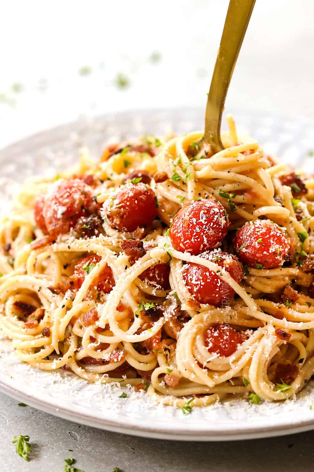 bacon pasta with tomatoes, garlic and Parmesan on a white plate