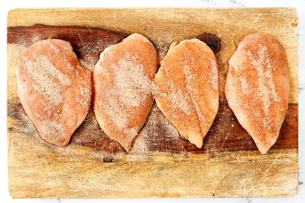 showing how to make blackened chicken recipe by seasoning chicken with blackening seasoning