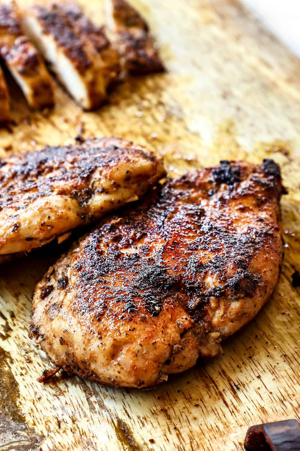 blackened chicken on a cutting board showing the blackened crust
