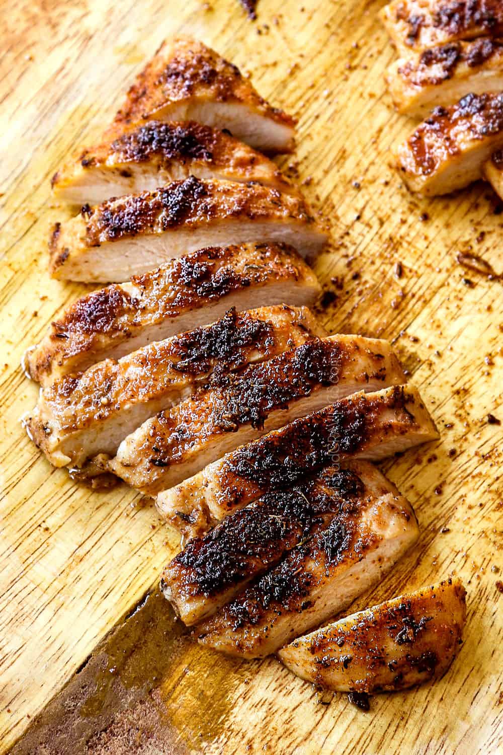 blackened chicken on a cutting board sliced into strips showing the charred crust