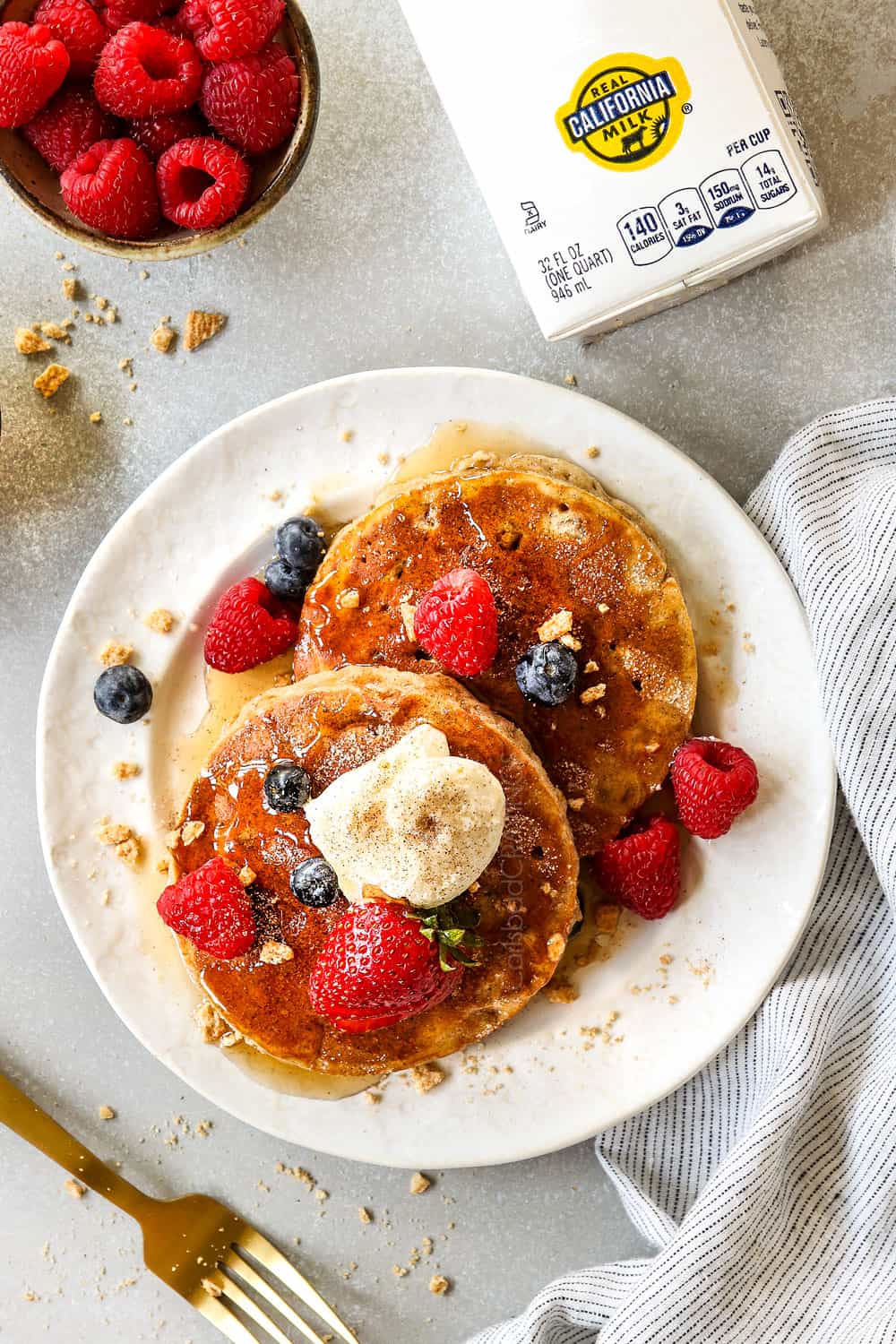 top view of cinnamon toast crunch cereal pancakes on a plate garnished with berries, cinnamon and sugar
