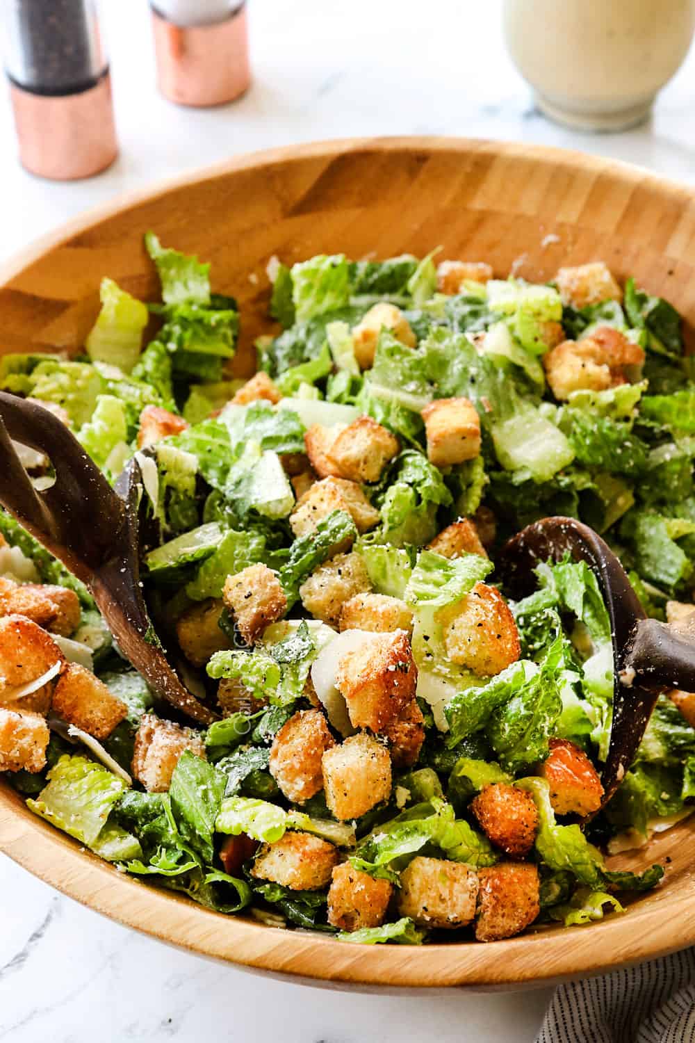 showing how to make Caesar Salad by tossing the ingredients together