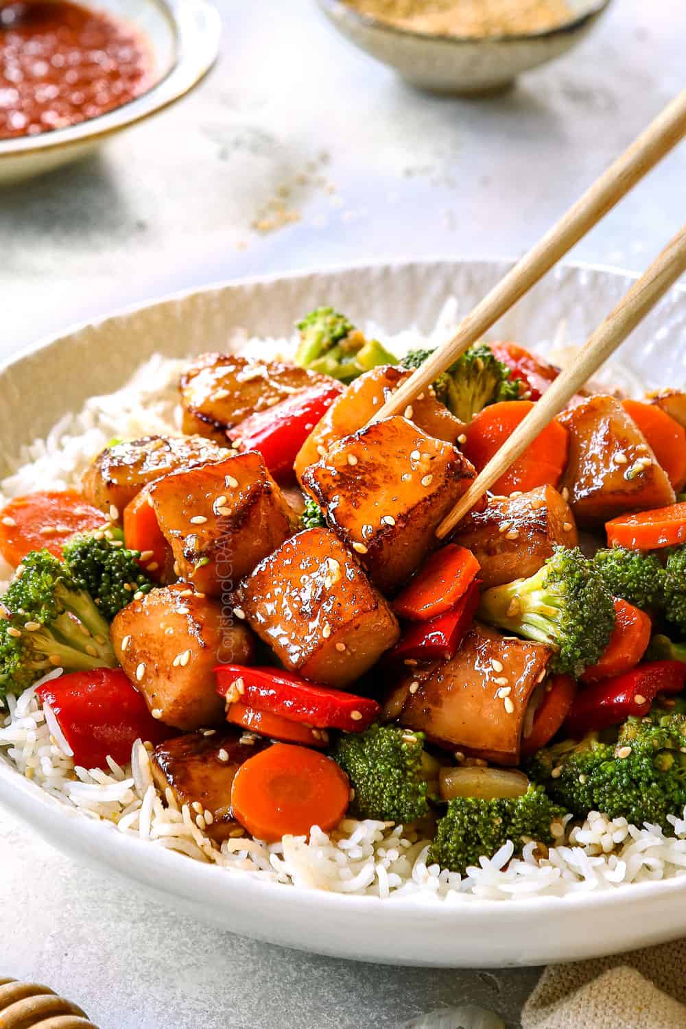 picking up a piece of Chinese honey garlic chicken with chopsticks