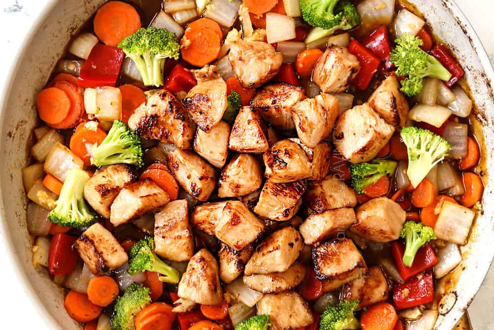 showing how to make honey garlic chicken stir fry recipe by adding chicken and sauce to the vegetables in the skillet